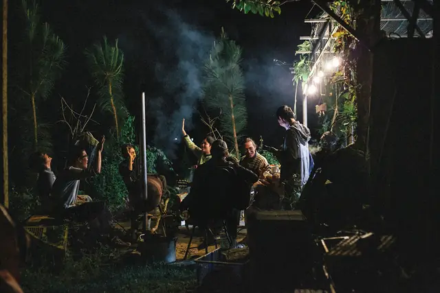 A circle of friends gathered at night under garden lights