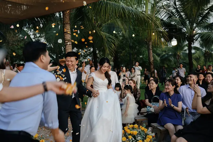 A bride and groom walking through falling flower petals at a garden wedding